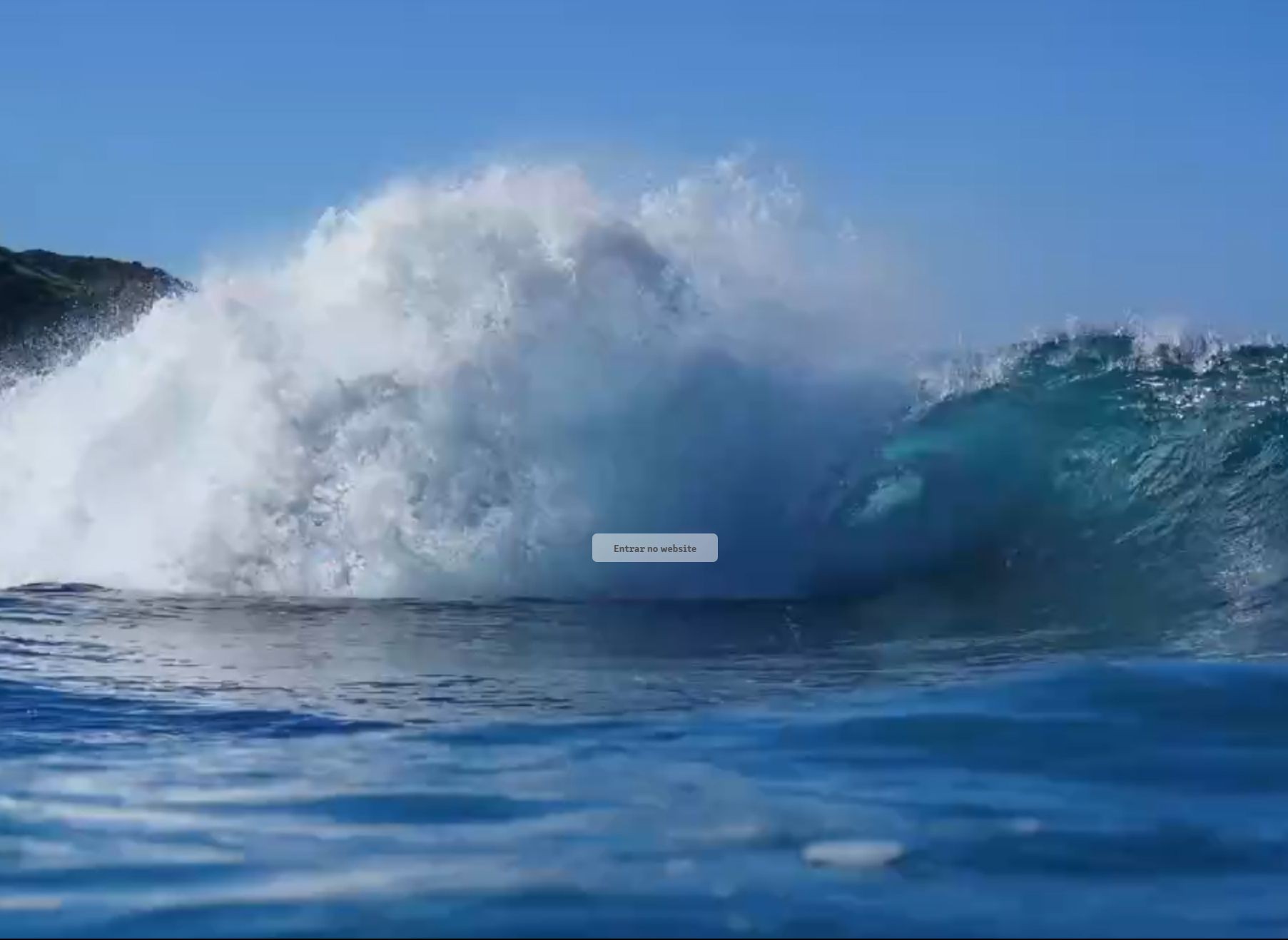 Large ocean wave crashing with white foam under a clear blue sky.